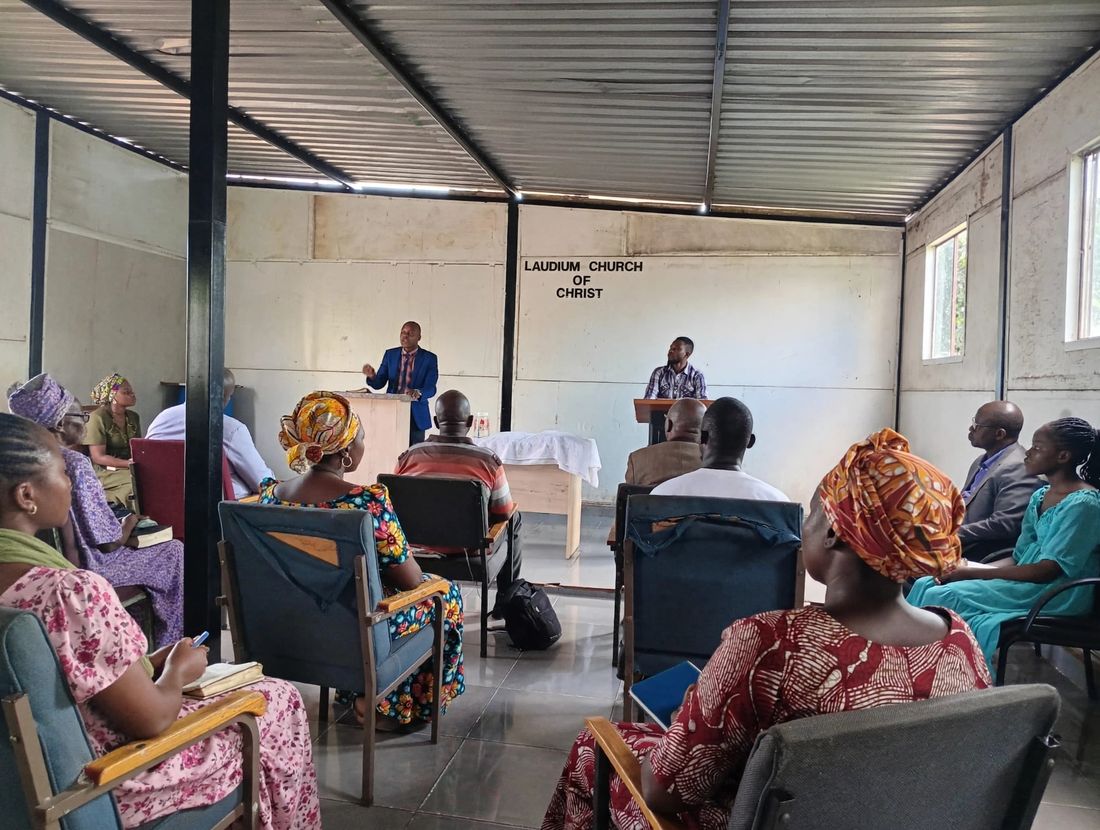 Members of our church of Christ in Laudium sit in blue chairs facing a preacher at a wooden stand
